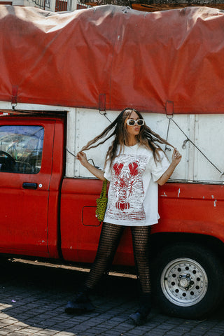 Woman posing in front of a red truck with a white t-shirt and sunglasses.