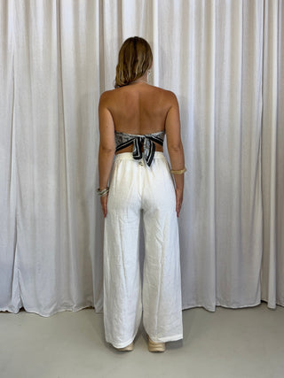 Person wearing a white dress standing against a white curtain.