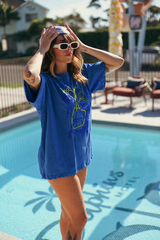 Person wearing a blue oversized t-shirt by a poolside