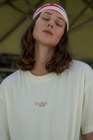 Person wearing a white t-shirt with a logo and a headband with red and white stripes.