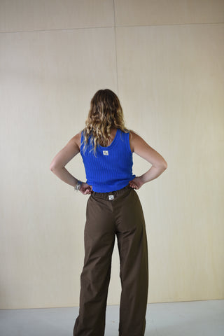 Person wearing a blue shirt and brown pants on a plain background
