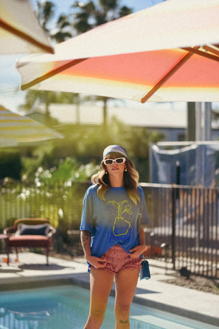 Woman by a pool under a colorful umbrella with a blurred background