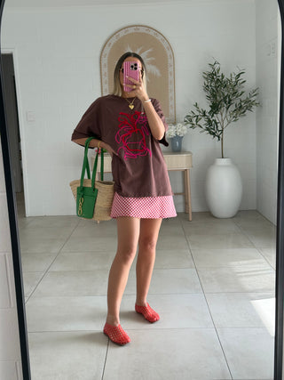 Stylish woman wearing brown tshirt with red gingham mini skirt