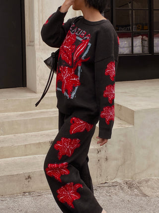 Person wearing a black outfit with red floral patterns on steps.