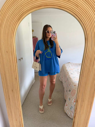 Person taking a mirror selfie wearing a blue outfit with a graphic design.