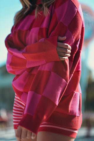 Person wearing a red and pink patterned sweater with blurred background