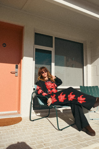 Person sitting on a chair outside a building with a pink door.