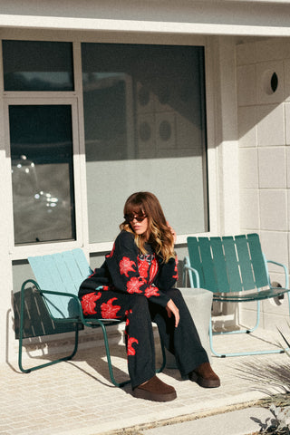 Woman sitting on a green chair in front of a building with large windows.