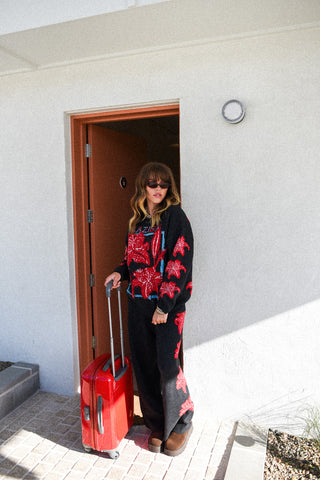 Person holding a red suitcase exiting a building